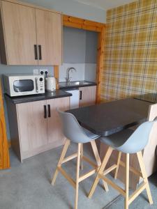a kitchen with a table and two chairs and a microwave at The Studio in Drumnadrochit