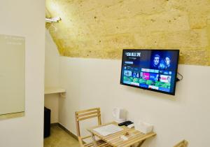 a room with a table and a tv on a wall at Arvian B&B in Bari