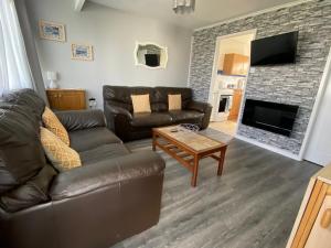 East Coast Chalets 57 at California Sands في Scratby: غرفة معيشة مع أريكة جلدية ومدفأة