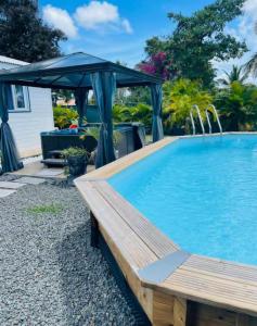 a swimming pool with a blue canopy and a wooden bench at BUNGALOW DE SAINT JACQUES in Saint-François +32 photos