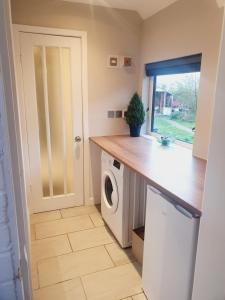 a laundry room with a washing machine and a window at Little Lupin in Loddon