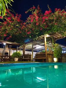 a swimming pool with pink flowers and a pergola at Muriú Beach Flat in Muriú