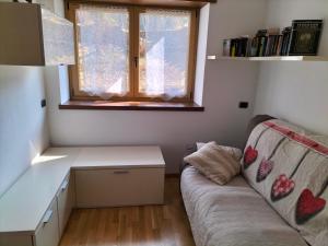 a living room with a couch and a desk and a window at Bernina Apartament in Chiesa in Valmalenco
