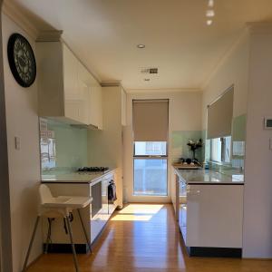 a kitchen with white cabinets and a clock on the wall at Gerring Court with Free 1 Car Bay Parking in Perth