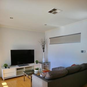 uma sala de estar com um sofá e uma televisão de ecrã plano em Gerring Court with Free 1 Car Bay Parking em Perth