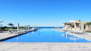a swimming pool with lounge chairs and the ocean at Encanto Living Two Bedroom Unit by Kivoya in Puerto Peñasco