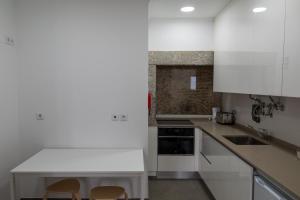 eine Küche mit weißen Schränken und 2 Stühlen in der Unterkunft Ajuda - Apartments in Lissabon