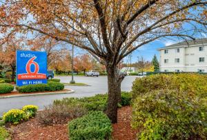 um sinal para um edifício monólogo com uma árvore em Motel 6 Fishers, In - Indianapolis em Fishers