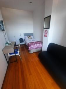 a room with a bed and a desk and a table at Hospedaje Lopez in A Coruña