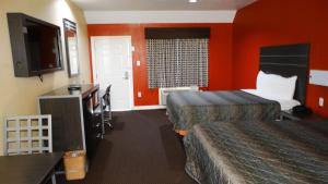 a hotel room with two beds and orange walls at Motel 6 Houston, TX – Willowbrook Mall in Houston