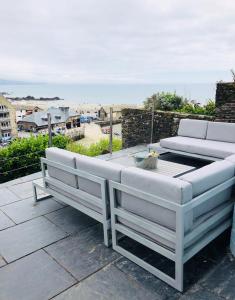 a couch and a table on a patio with the beach at Harbour House Looe in Looe