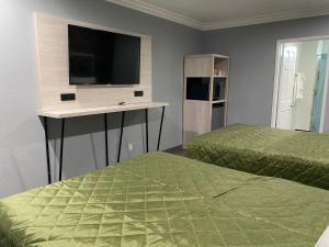a bedroom with two beds and a desk with a television at Harbor Inn in Harbor City