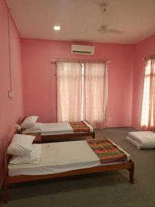 a bedroom with two beds and a pink wall at Homestay Machang Sentral in Machang