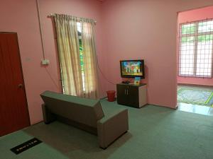 een woonkamer met een bank en een televisie bij Homestay Machang Sentral in Macang