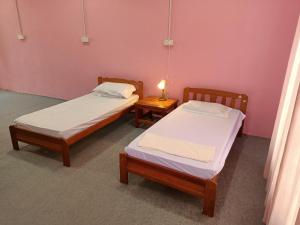 twee bedden in een kamer met roze muren bij Homestay Machang Sentral in Macang