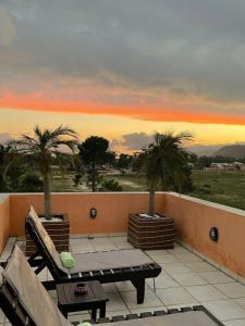 a balcony with a bench and palm trees at sunset at Pousada Ilha dos Anjos in Florianópolis