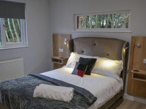 a bed in a bedroom with two windows at Serenity Lodge Otterburn in Otterburn