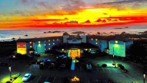 クレセントシティにあるOceanfront Lodgeの夕日を背景に海辺の建物