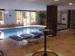 a swimming pool with blue chairs and a table and a tablektop at Hotel Villa Lehmi in Tárbena