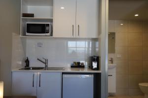 a kitchen with white cabinets and a sink and a microwave at Kallangur Motel in Kallangur