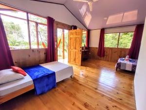 德雷克的住宿－The Sunset Tucano Lodge，一间卧室设有床铺和一些窗户,铺有木地板