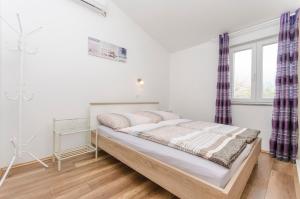 Bett in einem weißen Zimmer mit Fenster in der Unterkunft Apartments Anka in Vir