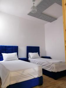 two beds in a room with white walls at Zom appartement in Dakhla