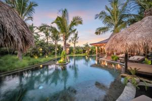 an infinity pool in a resort with palm trees at Desa Hay Canggu in Canggu