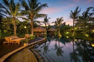 a resort pool with chairs and palm trees at night at Desa Hay Canggu in Canggu