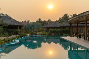 Authentic Khmer Village Resort في سيام ريب: مسبح في المنتجع وقت الغروب