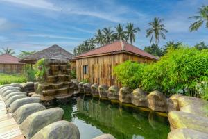 a house with a pond in front of a building at Authentic Khmer Village Resort in Siem Reap