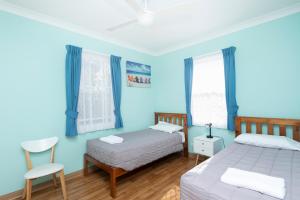 a blue bedroom with two beds and a chair at Forster Holiday Village in Forster