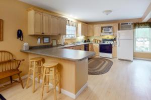 a kitchen with wooden cabinets and a island with bar stools at Beach Plum Townhouse in Ogunquit