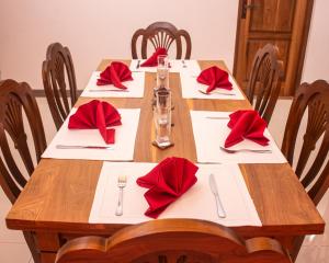 a long wooden table with red napkins and napkins at Danisco Leisure Bunglow in Kandy