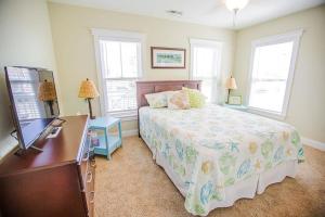 a bedroom with a bed and a dresser and two windows at Life's A Beach in Holden Beach +36 photos