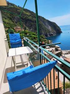 d'un balcon avec des chaises bleues, une table et l'océan. dans l'établissement LASOMMO 1, à Riomaggiore