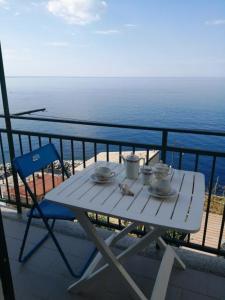 d'une table et d'une chaise blanches sur un balcon donnant sur l'océan. dans l'établissement LASOMMO 1, à Riomaggiore