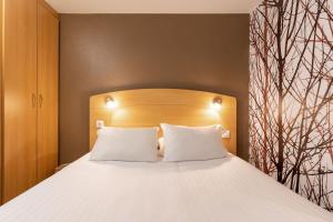a bed with white pillows and a wooden headboard at Sure Hotel by Best Western Plaisir in Plaisir +34 photos