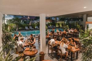 eine Gruppe von Personen, die in einem Restaurant mit Pool an Tischen sitzen in der Unterkunft Onederz Siem Reap in Siem Reap
