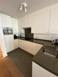eine Küche mit weißen Schränken und einer schwarzen Arbeitsplatte in der Unterkunft Julie’s Home in Knokke-Heist