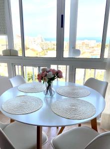 una mesa blanca con sillas blancas y un jarrón de flores en Iris Vistas Sea & Sun Benalmadena, en Benalmádena