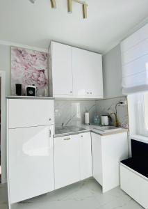 a white kitchen with white cabinets at Glamour Apartment przy plaży, z parkingiem prywatnym in Sopot
