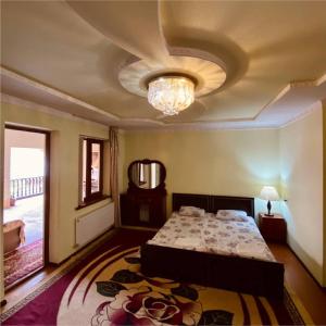 een slaapkamer met een bed en een plafond met een kroonluchter bij Hotel Rahmon in Samarkand