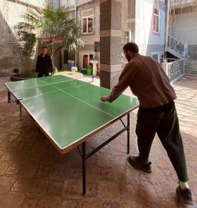 un hombre jugando ping pong en una mesa de ping pong en Hotel Rahmon, en Samarkand