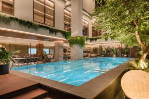 a large pool in a hotel with tables and chairs at Ashley Tanah Abang in Jakarta