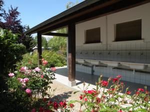 Tente Bell au camping Hautoreille في Bannes: حديقة بها زهور وردية ومبنى