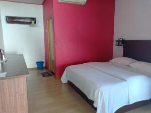 a bedroom with a white bed and a pink wall at Suhaila Palace in Perhentian Islands
