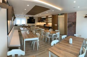 a restaurant with wooden tables and white chairs at Žigon Bed & Breakfast in Logatec
