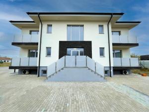 a large white building with stairs in front of it at Apartmány Katalin in Dunajská Streda