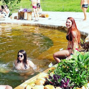 deux femmes assises dans l'eau dans une piscine dans l'établissement Pousada Lenda da Montanha, à Aiuruoca